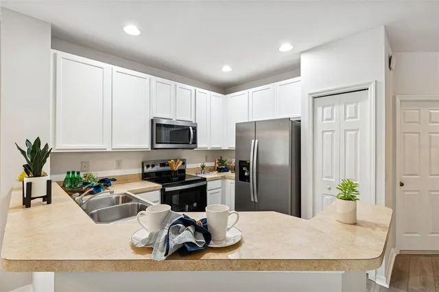 a kitchen with stainless steel appliances granite countertop sink stove refrigerator and cabinets