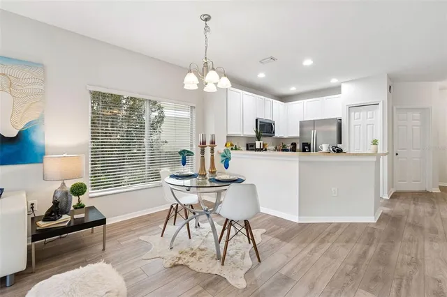 a view of a dining room and livingroom with furniture wooden floor a chandelier