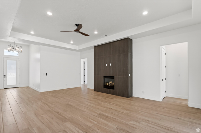2862 South Mountain Rnch Road Cedar City, UT 84720 - Photo 8 of 64 Spacious living area featuring wood-finish flooring, a modern fireplace with a dark wood-finish surround, a contemporary ceiling fan, recessed lighting, and a tray ceiling