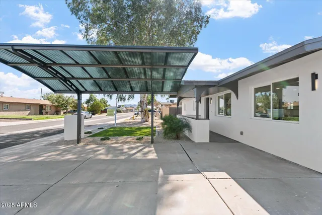 a view of a patio with table and chairs under an umbrella with a barbeque
