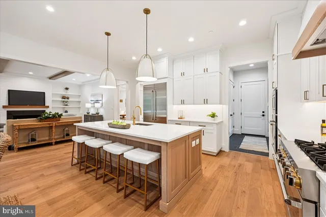 a kitchen with stainless steel appliances kitchen island granite countertop a stove a sink a refrigerator and a dining table with wooden floor