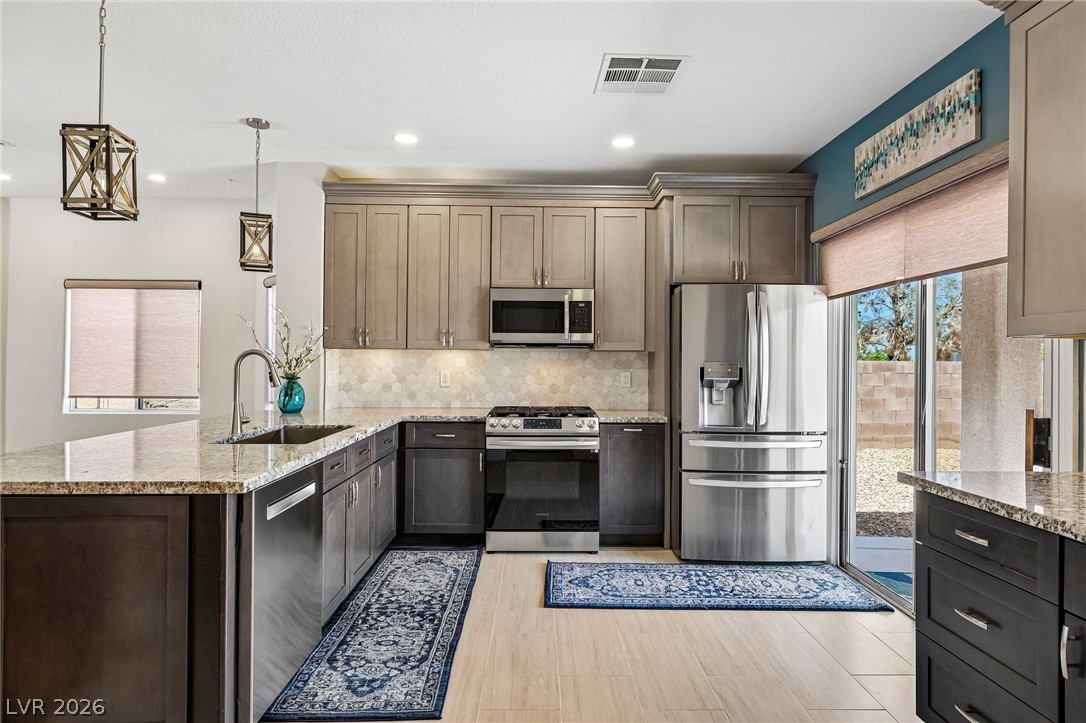 1176 Butternut Ranch Court Henderson, NV 89052 - Photo 13 of 60 A well-appointed kitchen boasts granite counters, stainless steel appliances, and sleek wood flooring, perfect for culinary endeavors.