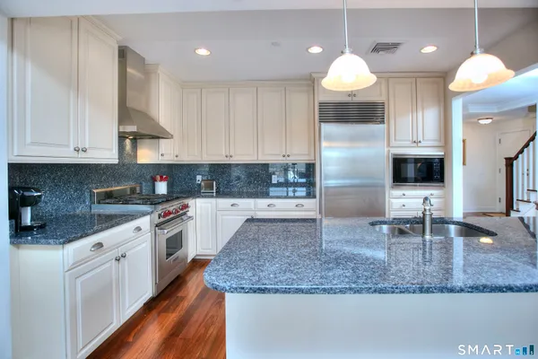 a kitchen with stainless steel appliances granite countertop a sink a stove and a refrigerator