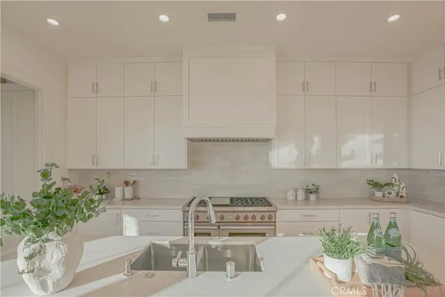 a kitchen with stainless steel appliances kitchen island granite countertop a sink and white cabinets