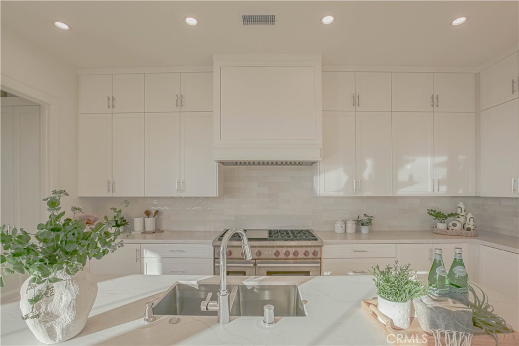 137 Oakstone Irvine, CA 92618 - Photo 14 of 54 a kitchen with stainless steel appliances kitchen island granite countertop a sink and white cabinets