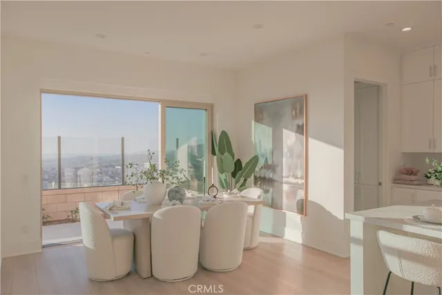 a dining room with furniture a potted plant and a large window
