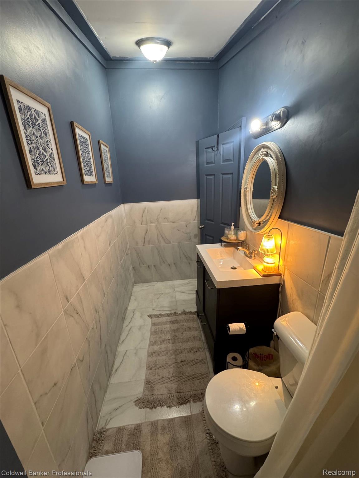 5323 English Road Clifford, MI 48727 - Photo 34 of 46 Vanity with an integrated sink, wall-mounted light fixture, and floor-to-ceiling wall tiling