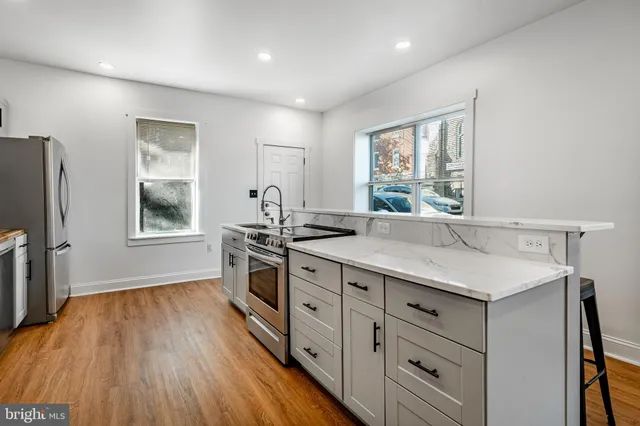 a kitchen with stainless steel appliances granite countertop a sink cabinets and wooden floor