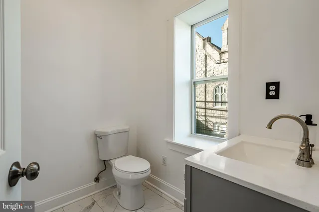 a bathroom with a sink a toilet and a window