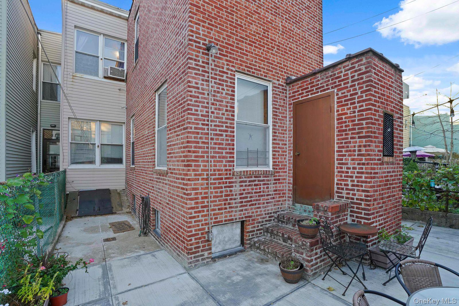 1920 Palmetto Street Queens, NY 11385 - Photo 22 of 26 a brick house with a yard and table and chairs