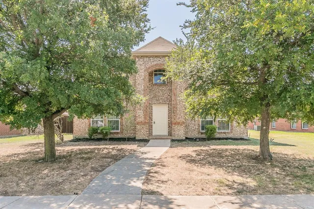 a front view of a house with a yard and large trees