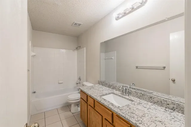 a bathroom with a granite countertop sink a toilet and shower