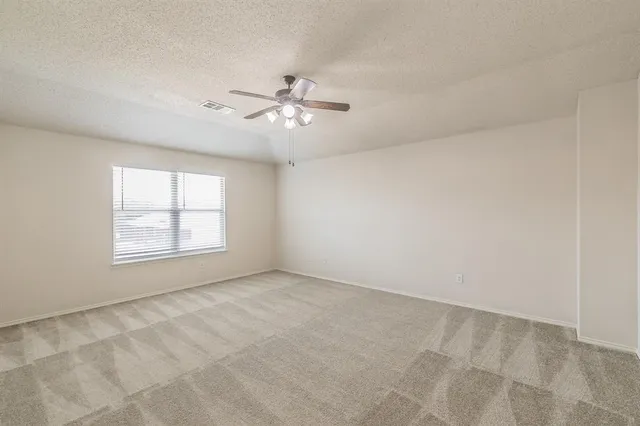 an empty room with chandelier fan and windows