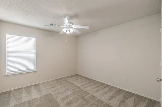an empty room with a window and a ceiling fan