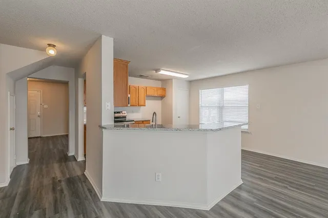 a living room with stainless steel appliances wooden floors and large window