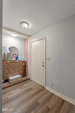 a view of a hallway to room with wooden floor and fan