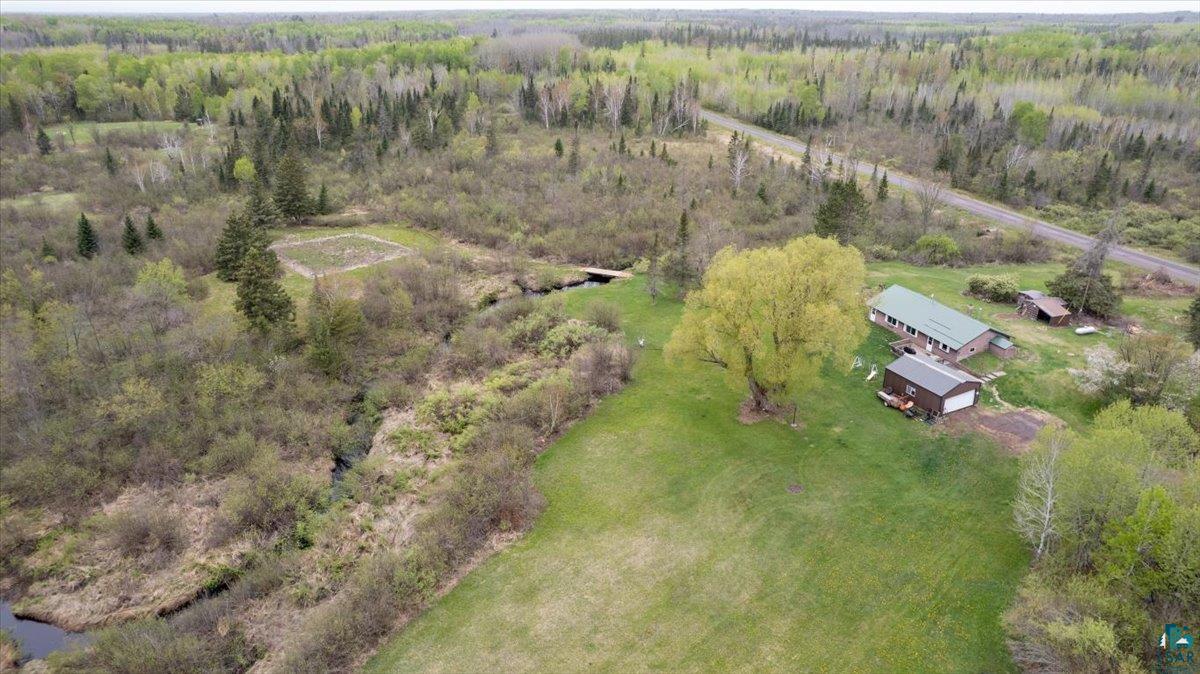 5190 County Road M Gordon, WI 54838 - Photo 30 of 31 Expansive acreage featuring a main residence with a green metal roof, an additional outbuilding, and a large mature tree