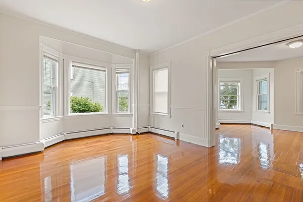 a view of an empty room with wooden floor and a window