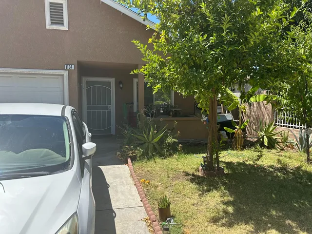 a view of a house with a small yard and large tree