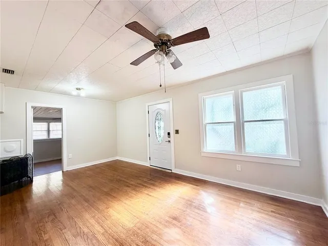 a view of an empty room with a window and wooden floor