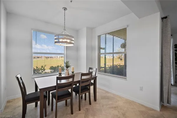 a large white kitchen with a white countertops a stove a couch and a dining table with wooden floor