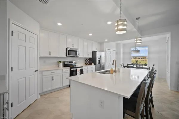 a kitchen with stainless steel appliances granite countertop a stove refrigerator a sink a dining table and chairs