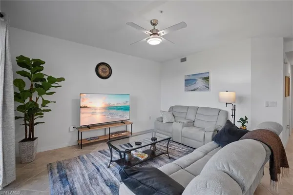 a living room with furniture kitchen view and a chandelier