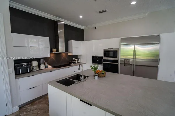 a kitchen with stainless steel appliances a sink a stove a microwave a refrigerator and cabinets