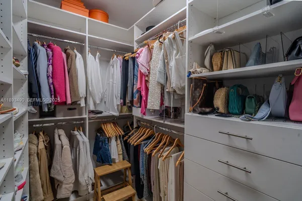 a view of walk in closet with clothes and shoes