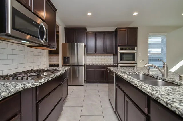 a kitchen with stainless steel appliances granite countertop a sink stove and refrigerator