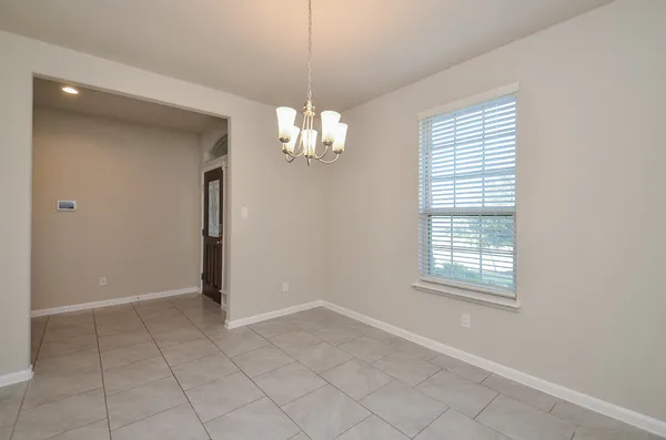 an empty room with chandelier fan and windows