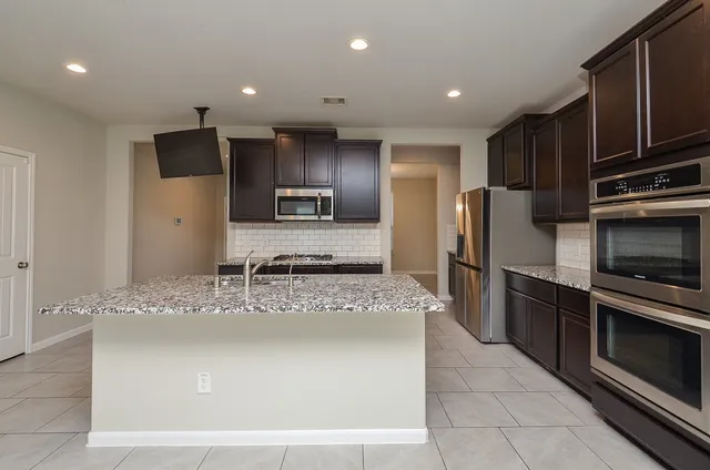 a kitchen with stainless steel appliances granite countertop a sink refrigerator and microwave