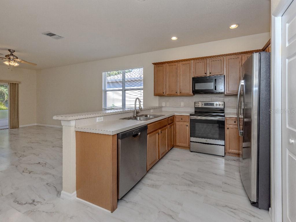 11649 Tempest Harbor Loop Venice, FL 34292 - Photo 6 of 39 a kitchen with stainless steel appliances granite countertop a stove top oven a sink and a granite counter tops