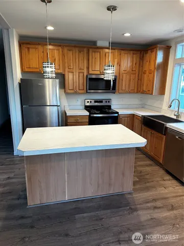 a kitchen with stainless steel appliances a kitchen island hardwood floor sink stove dining table and chairs