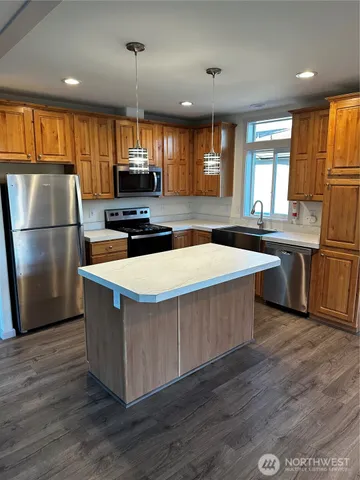 a kitchen with stainless steel appliances a stove a sink a refrigerator and a center island