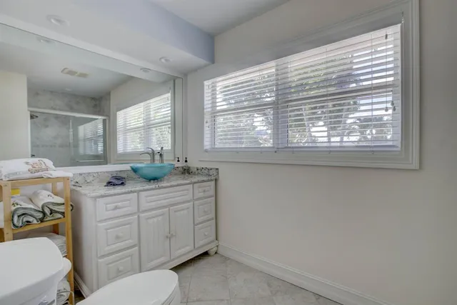 a spacious bathroom with a granite countertop toilet a sink a mirror and a window