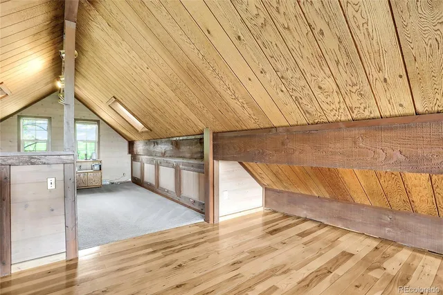 a view of an empty room with wooden floor and fence