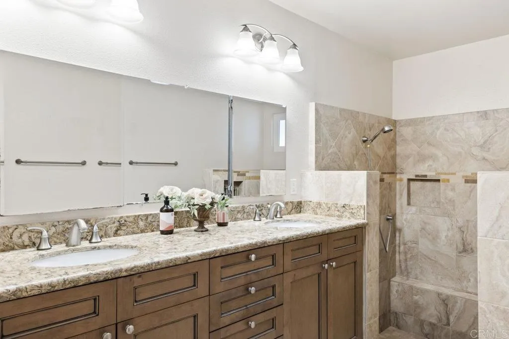 6825 Kellyn Lane Vista, CA 92084 - Photo 30 of 65 a bathroom with a granite countertop sink double mirror and shower