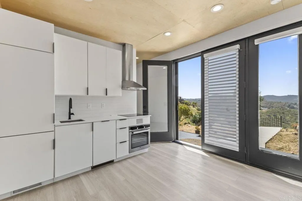 6825 Kellyn Lane Vista, CA 92084 - Photo 46 of 65 a kitchen with stainless steel appliances white cabinets and wooden floor