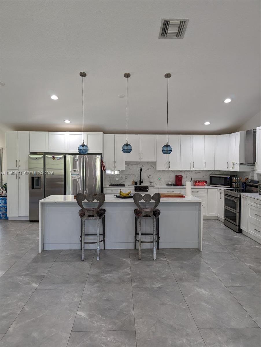 10920 Barn Road Lake Worth, FL 33449 - Photo 13 of 19 a kitchen with stainless steel appliances kitchen island granite countertop a sink and white cabinets
