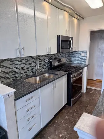 a kitchen with granite countertop stainless steel appliances a stove microwave and sink