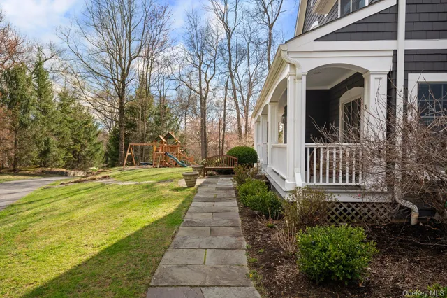 a view of a house with large trees next to a yard