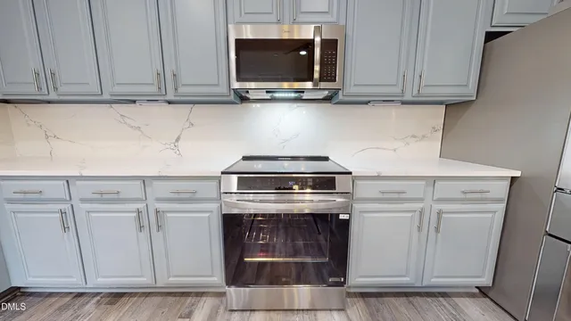 a kitchen with stainless steel appliances granite countertop a refrigerator stove and white cabinets