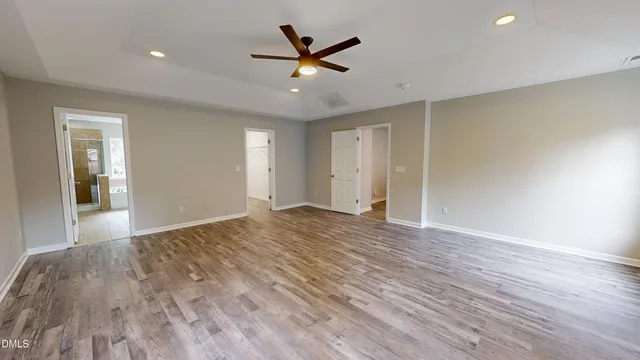 a view of empty room with wooden floor and fan