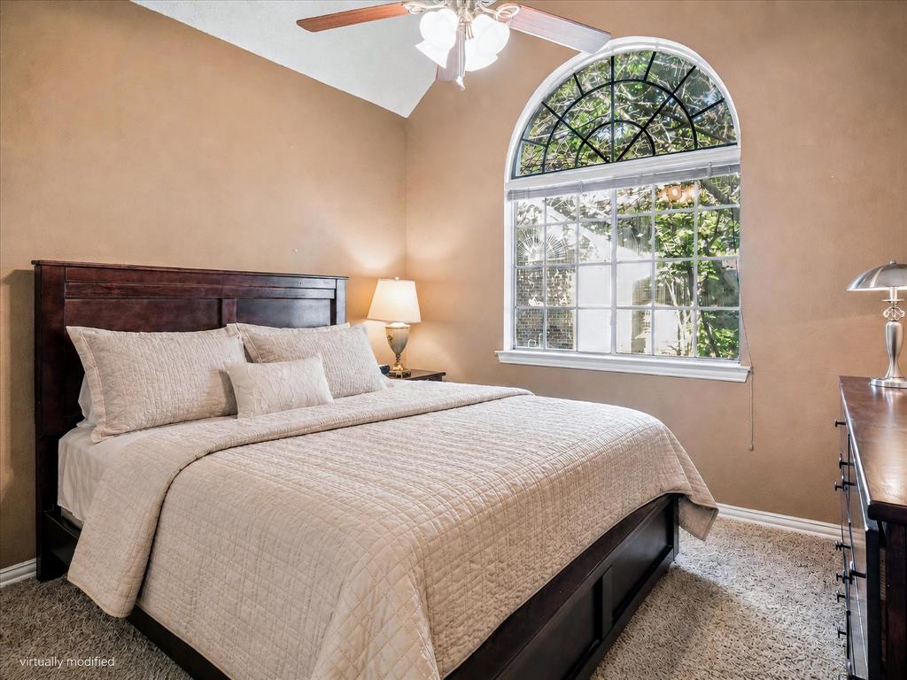 14592 Greenleaf Court Addison, TX 75001 - Photo 23 of 34 Bedroom featuring a large arched window with detailed muntins, vaulted ceiling, ceiling fan, and light-colored carpet flooring