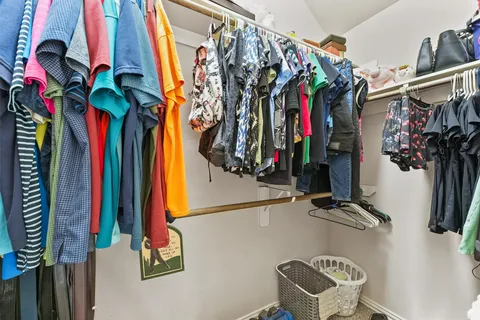 a view of walk in closet with clothes and shoes