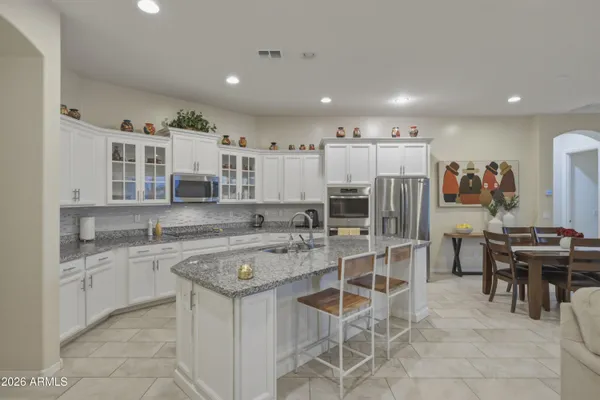 a kitchen with stainless steel appliances kitchen island granite countertop a table and chairs in it