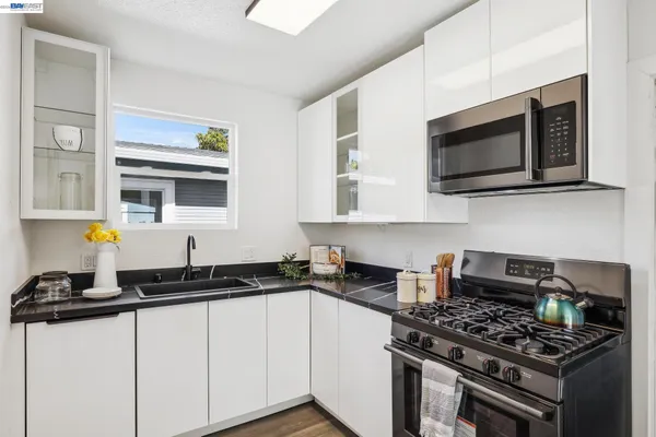 a kitchen with stainless steel appliances a white cabinet and a stove top oven