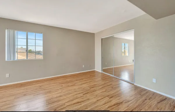 a view of an empty room with wooden floor and a window