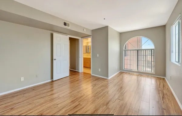 a view of an empty room with wooden floor and a window